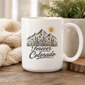 White 15 ounce ceramic Forever Colorado mug with mountain and wildflower illustration