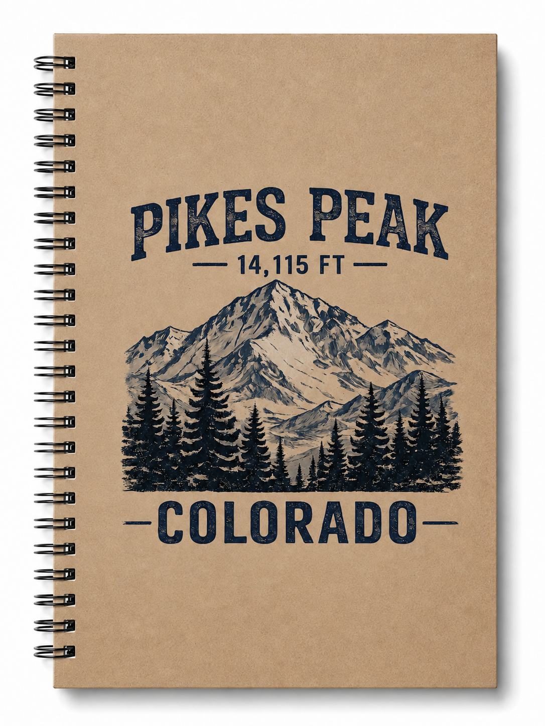 A spiral-bound notebook with a kraft paper cover featuring a dark blue graphic of Pikes Peak, Colorado, with the text 'PIKES PEAK 14,115 FT' and 'COLORADO' above and below the mountain illustration.