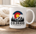 White 15 ounce ceramic Colorado Elevated mug with mountain, trees, and Colorado flag-inspired design